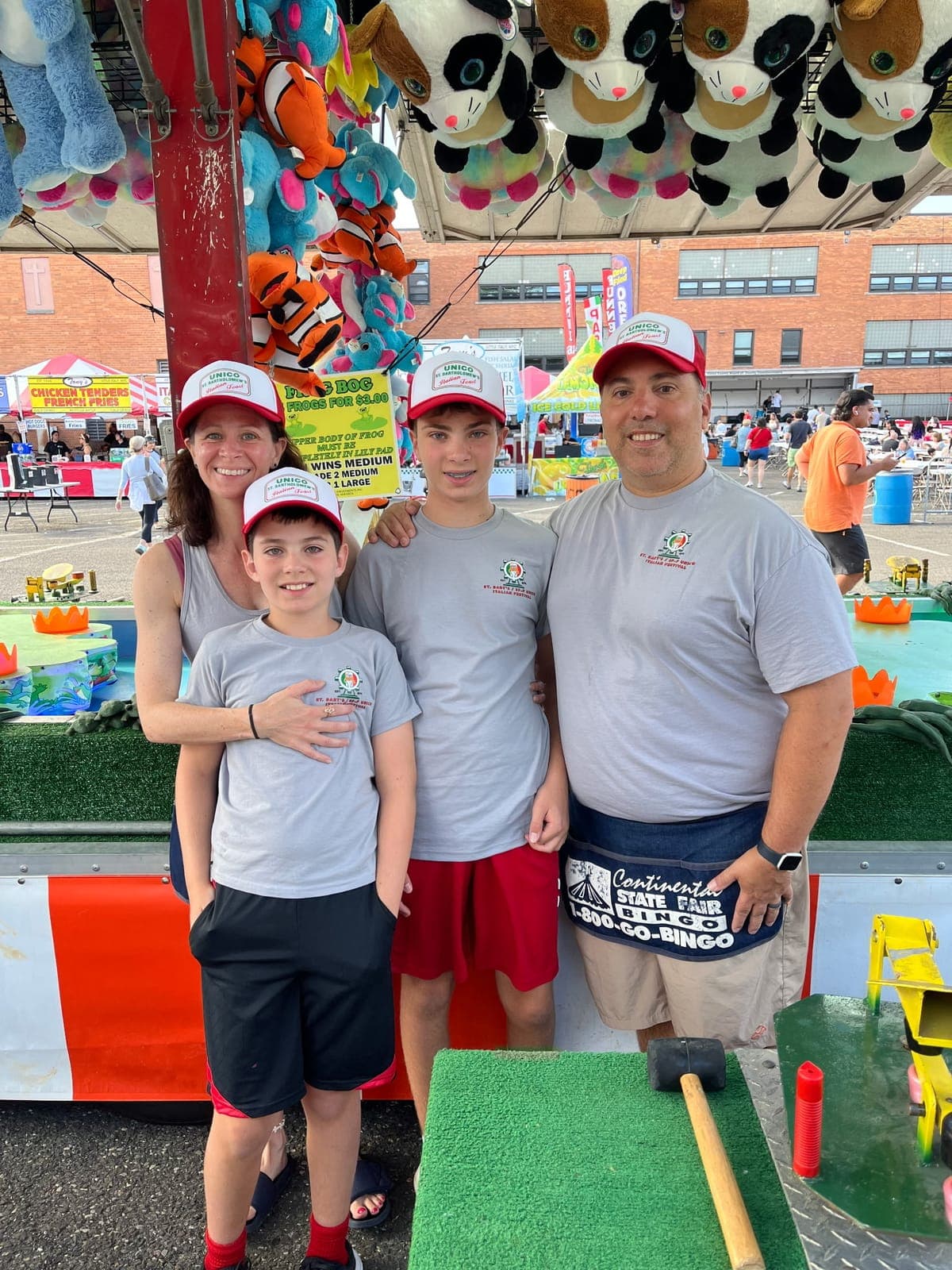 Festival volunteers and families gather at a midway game during the Labor Day Italian Festival.