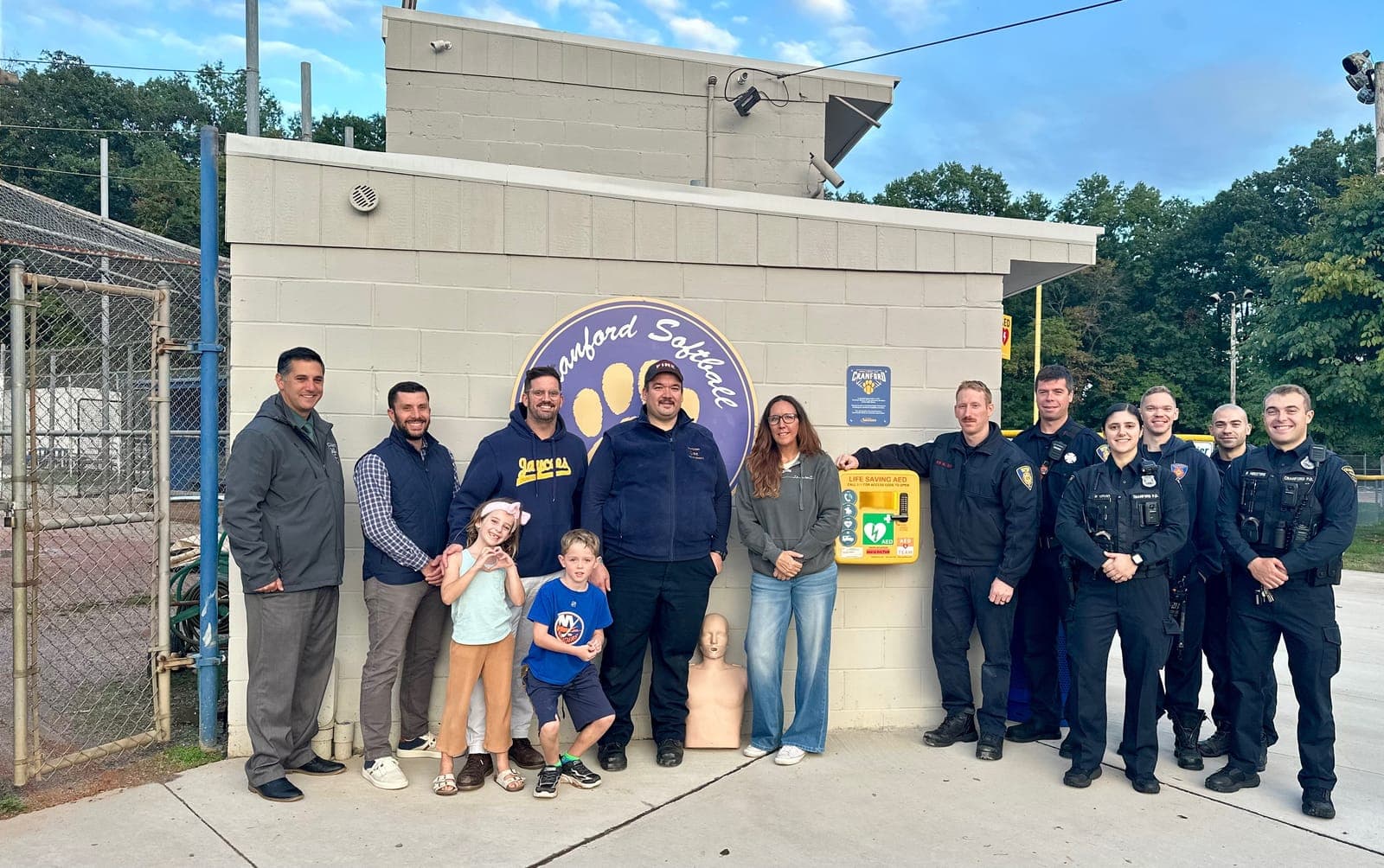 Members of the Cranford Jaycees, CBSL, The Aliver Foundation, CFD, and CPD gather around the outdoor AED equipment at Adams Field House.